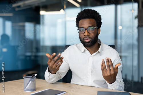 Cuadro en lienzo An African American man wearing glasses seriously communicates during a video ca