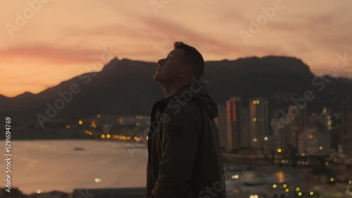 Young man enjoying the sunset alone overlooking the city of Calpe, Spain