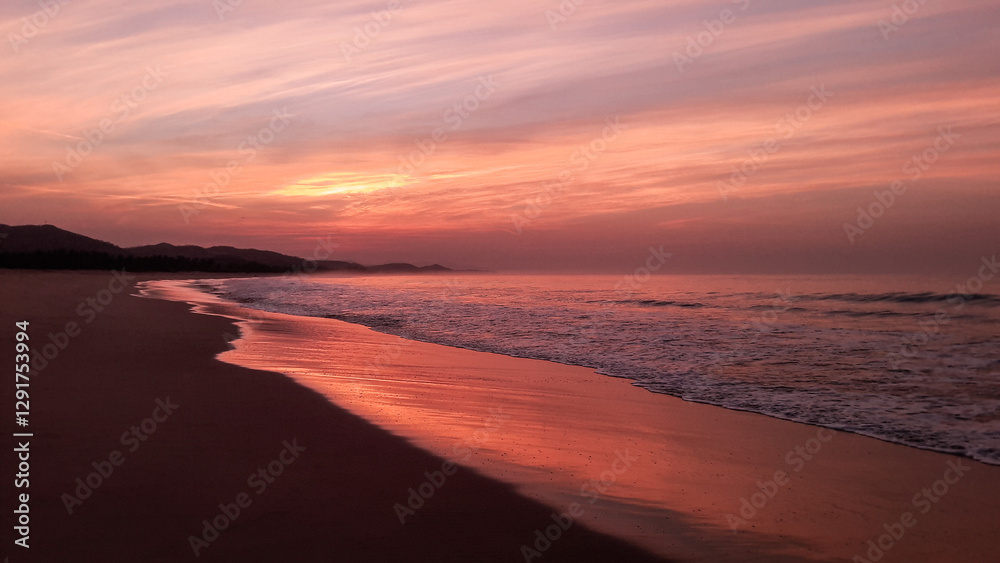 Obraz premium amanecer o atardecer en una playa con olas y brisas con cielo rojizo, nubescoloridas y agua de mar reflejando el cielo