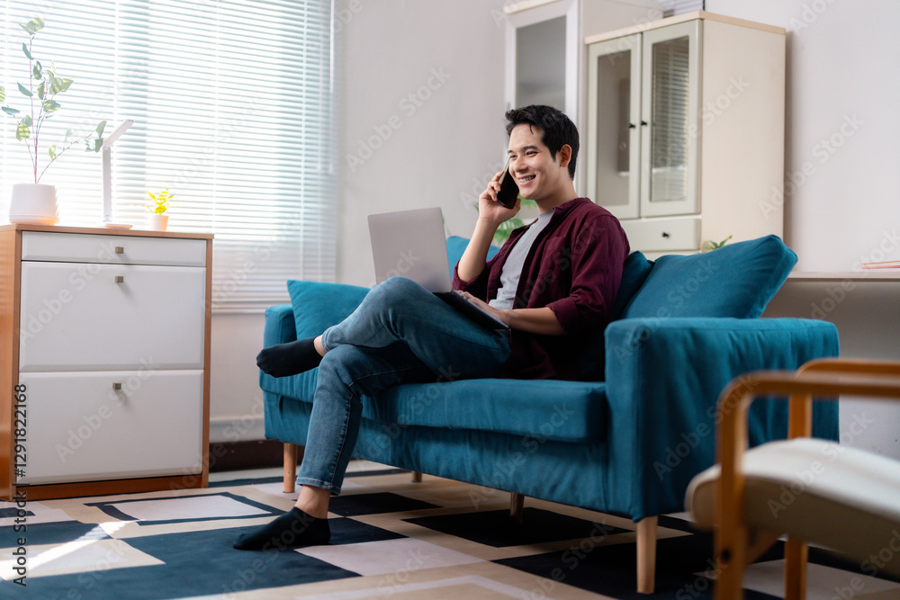 Asian Freelancer Talking on Phone and Working on Laptop at Home Asian Freelancer Talking on Phone and Working on Laptop at Home