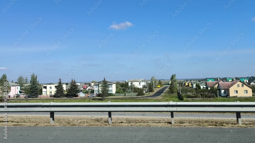 Obraz premium Country houses along the road in summer. Private houses, quiet streets along the highway in summer.