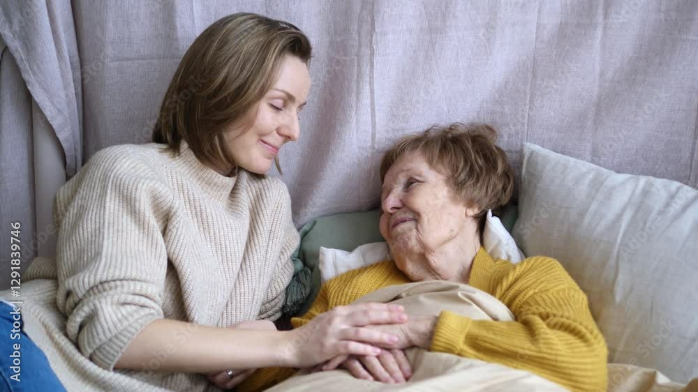 Granddaughter shows caring for sick grandmother in bed. Caring for older generation, woman tenderly holds hand sick. Caring for elderly relatives, connection between generations, love and attention. Granddaughter shows caring for sick grandmother in bed. Caring for older generation, woman tenderly holds hand sick. Caring for elderly relatives, connection between generations, love and attention.