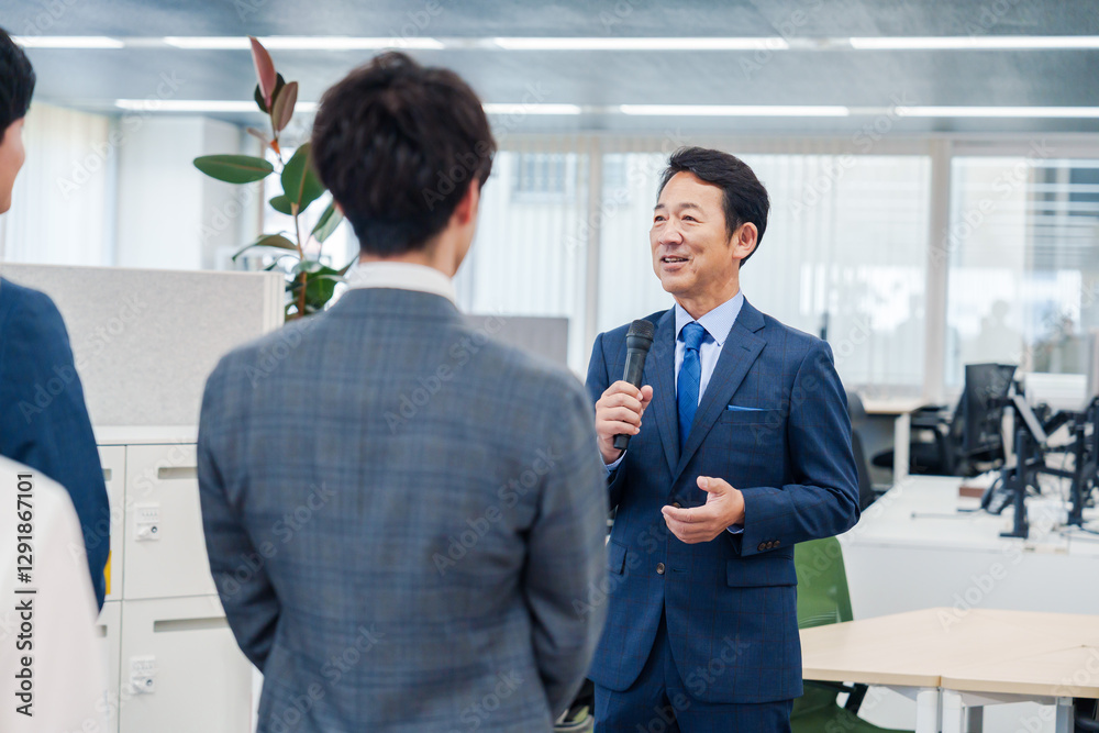 オフィスでの朝礼で挨拶をする管理職の男性 オフィスでの朝礼で挨拶をする管理職の男性