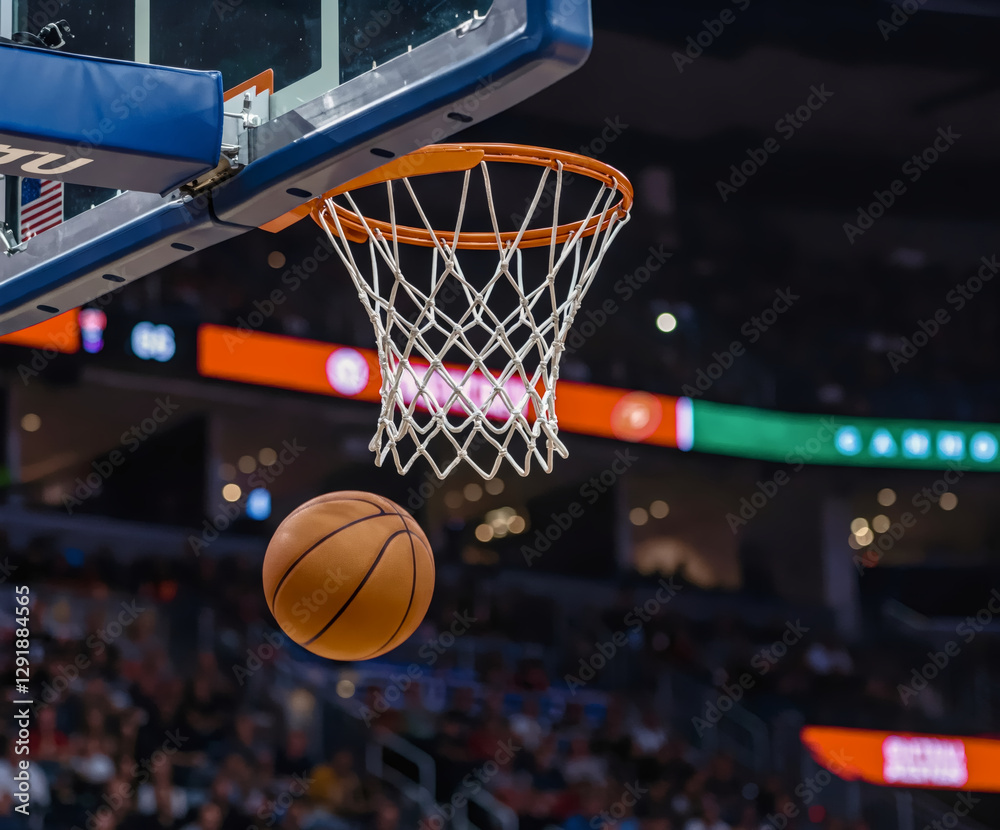 Fototapeta premium Slam Dunk Moment: A basketball, suspended in mid-air, streaks towards the net as it captures the intensity of a sporting event. The image exudes dynamism, emphasizing the perfect harmony of sport.