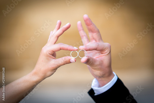manos sujetando los anillos de recién casados con los dedos y chocándolos