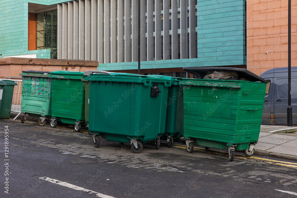 Row of Large Outdoor Commercial Green Recycling Waste Bins on City Asphalt Street Row of Large Outdoor Commercial Green Recycling Waste Bins on City Asphalt Street