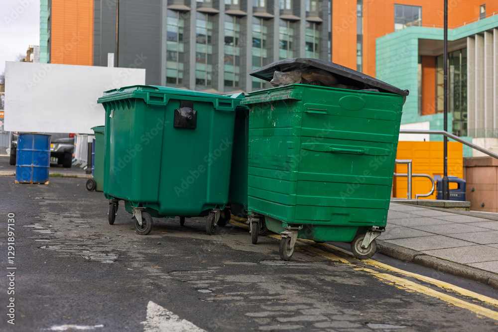 Row of Large Outdoor Commercial Green Recycling Waste Bins on City Asphalt Street Row of Large Outdoor Commercial Green Recycling Waste Bins on City Asphalt Street