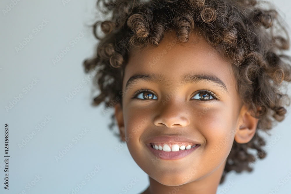 A cheerful young boy with curly hair smiling brightly against a simple background. A cheerful young boy with curly hair smiling brightly against a simple background.