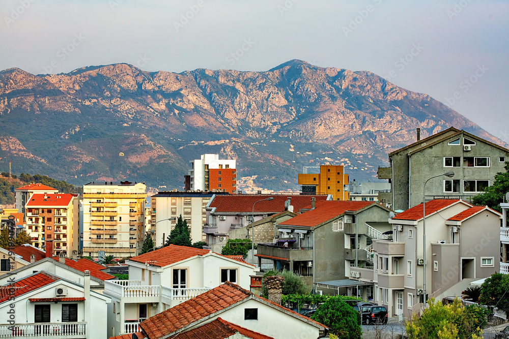 A mountain backdrop overlooking the bustling hillside district of Budva at dusk.