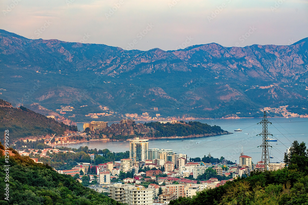 A picturesque view of the coastal town of Budva nestled between mountains at dusk.