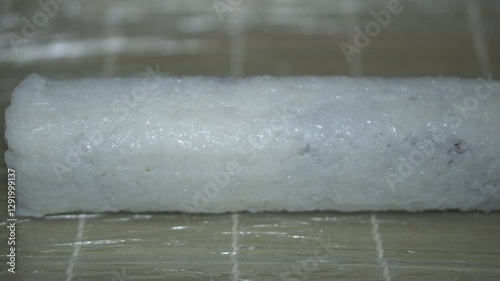 Chef in gloves preparing fish sushi roll