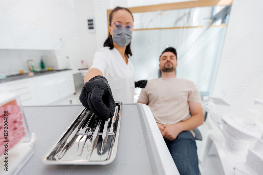 Obraz premium Dentist prepares tools while patient relaxes in a bright modern dental clinic setting
