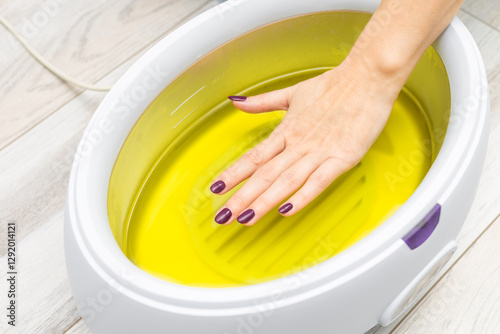 Fotografie a woman's hand is dipped into melted paraffin