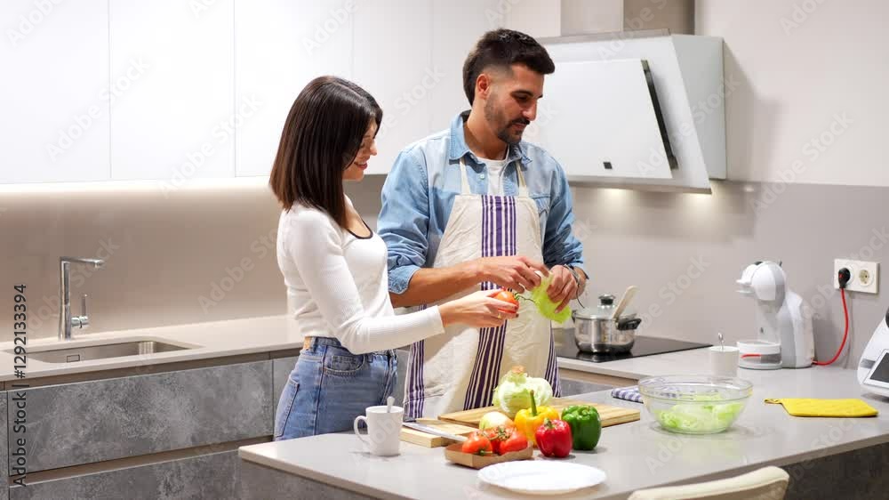 Cheerful young couple preparing vibrant salad together, sharing culinary moment in sleek kitchen space while chopping fresh vegetables Cheerful young couple preparing vibrant salad together, sharing culinary moment in sleek kitchen space while chopping fresh vegetables