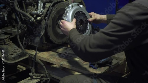 Auto mechanic installs clutch assembly. Hands expertly navigate flywheel, pressure plate, friction disc installation gearbox maintenance underway in workshop.