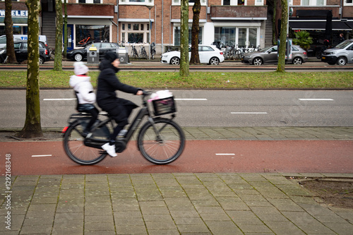 Woman riding electric bicycle with child on bike path in urban setting