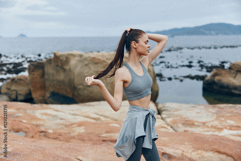Fit young woman in sportswear enjoying nature by the sea, showcasing a healthy lifestyle and physical fitness, with a tranquil coastal background and natural colors Fit young woman in sportswear enjoying nature by the sea, showcasing a healthy lifestyle and physical fitness, with a tranquil coastal background and natural colors