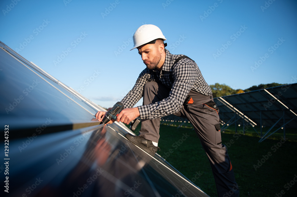 Worker installing solar panel on metal beams at sunny daytime. Renewable and ecological energy. Idea of environment safe. Modern technology and innovation. Man wearing workwear and helmet Worker installing solar panel on metal beams at sunny daytime. Renewable and ecological energy. Idea of environment safe. Modern technology and innovation. Man wearing workwear and helmet