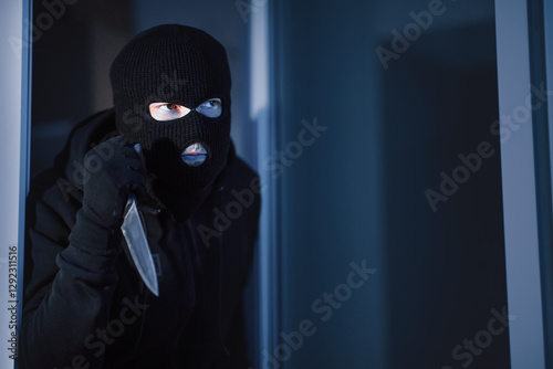 Violence Concept. Disguised prowler entering office through window or glass door with cold steel, searching for victim