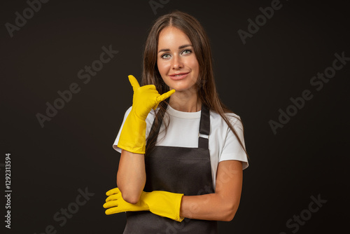 young attractive woman in an apron and rubber gloves shows a call me sign