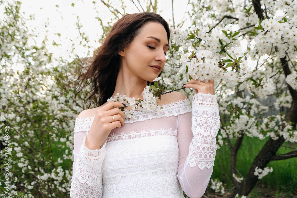 Romantic young woman in white dress enjoying the scent of blooming cherry tree flowers in a spring garden, celebrating the beauty of nature and the arrival of warm season Romantic young woman in white dress enjoying the scent of blooming cherry tree flowers in a spring garden, celebrating the beauty of nature and the arrival of warm season