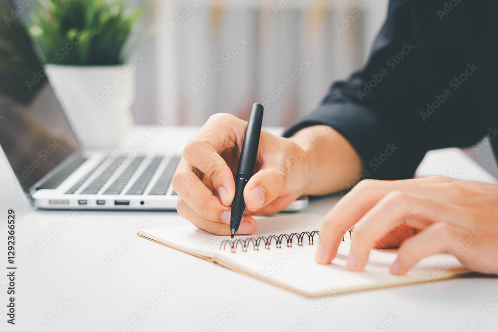 Fototapeta premium A close-up of a hand holding a pen, writing on a document for professional purposes.