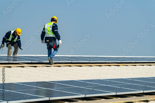 Wallpaper Mural Two engineers install solar panels on a rooftop, wearing safety gear and helmets. The scene showcases renewable energy, green technology, and sustainable solutions under a clear blue sky. Torontodigital.ca