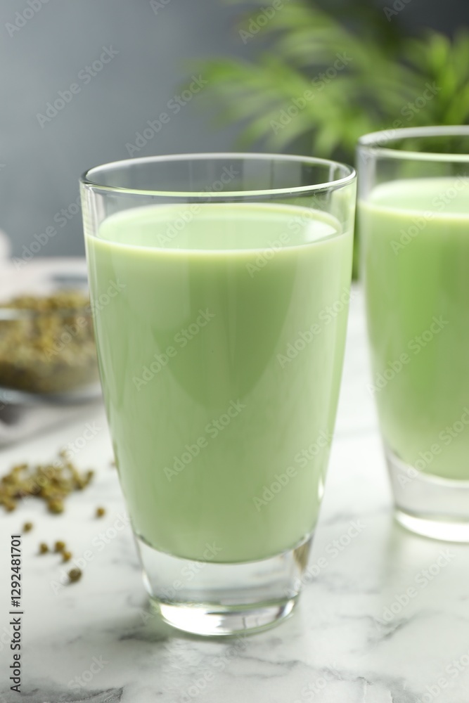 Fresh mung bean juice in glasses and seeds on white marble table, closeup Fresh mung bean juice in glasses and seeds on white marble table, closeup