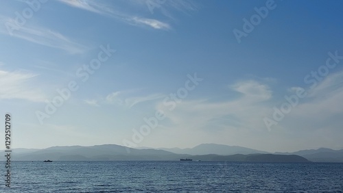 serene coastal scene calm ocean extending into the horizon under a bright blue sky filled with scattered