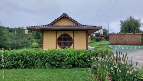 Traditional Japanese garden pavilion surrounded by lush greenery and trees with sunlight filtering through. Zen and tranquility concept for design and print