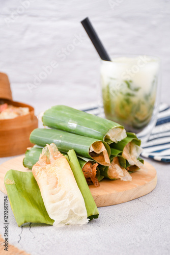 Serabi Solo on wooden plate. Traditional pancakes from Solo, Central Java. Made from flour dough baked on a special clay plate. Filled with various toppings then wrapped with banana leaf rolls photo