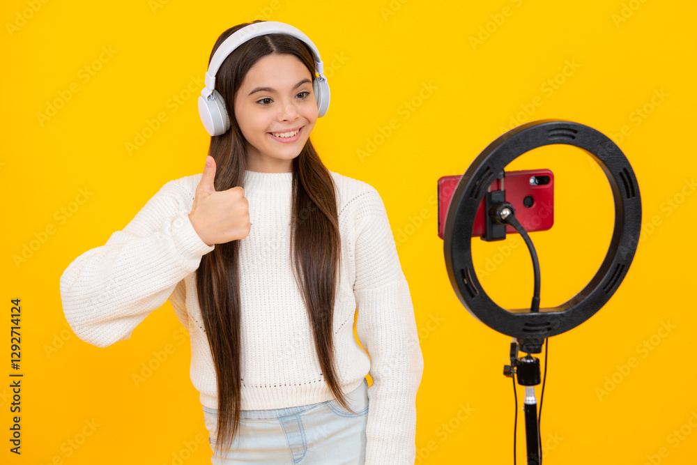 Teenager recording online media video. Teen girl streaming online and sharing social media content by mobile phone app network, isolated on yellow studio background. Teenager recording online media video. Teen girl streaming online and sharing social media content by mobile phone app network, isolated on yellow studio background.