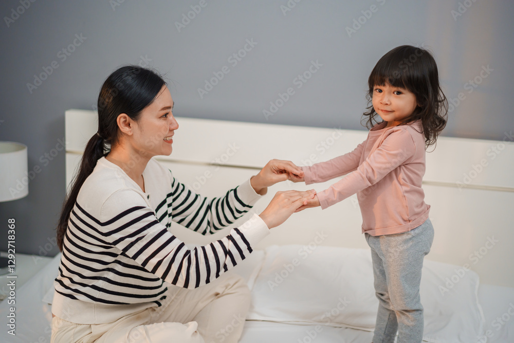 mother and toddler baby girl holding hands on bed mother and toddler baby girl holding hands on bed