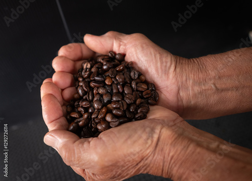 Close-up of a man holding a roasted coffee bean.