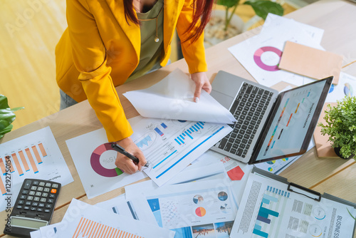 businesswoman hand closeup Deciphering some business data graph charts and laptop for marketing analyzing and business strategic planning in co-working office Analyzing business charts