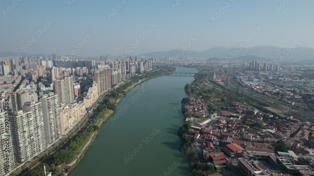 View of a dense building complex along a river in a rapidly developing city during clear weather View of a dense building complex along a river in a rapidly developing city during clear weather
