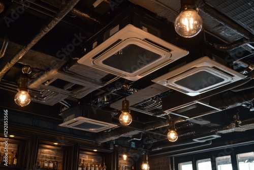 Ceiling installed cassette air conditioners with ventilation components in a commercial space featuring hanging lights and construction elements