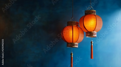 Two illuminated orange Chinese lanterns hang against a blue background photo