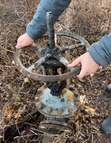 A rusty old valve is being held by a person's hands photo