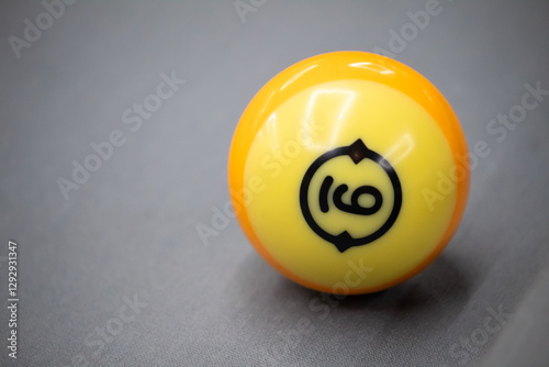 A close-up shot of a billiard ball, specifically the number 9 ball, resting on a green felt surface. The image captures the vibrant yellow color and bold black number