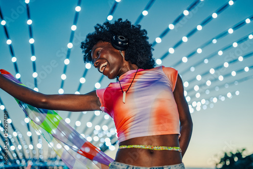Young woman dancing with scarf and headphones at music festival