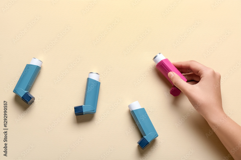 Child's hand with asthma inhalers on beige background Child's hand with asthma inhalers on beige background
