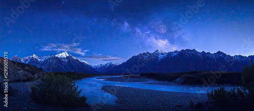 Majestic blue night sky revealing the Milky Way and zodiacal light over serene river winding through rugged mountains under starry illumination