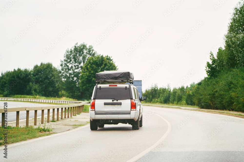 Obraz premium SUV with roof sleeping tent in motion on the highway