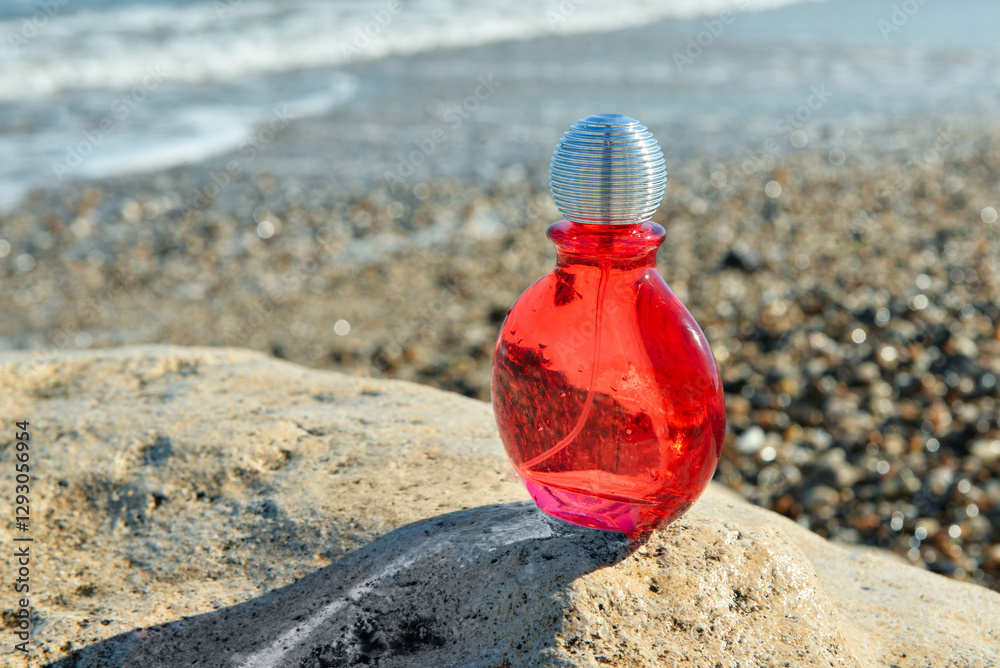 Bottle of elegant perfume on stone near ocean