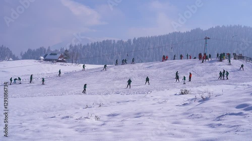 wide angle shot showing a huge group of people learning skiing on a beautiful small snow covered slope in Gulmarg Kashmir a popular resort and tourist destination in India