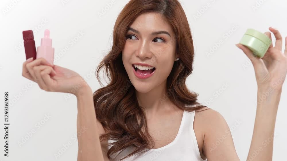 Smiling Asian woman showcasing skincare products in a bright studio against a white background Smiling Asian woman showcasing skincare products in a bright studio against a white background