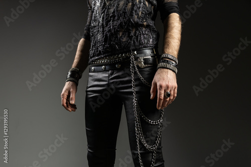 A bold and stylish rock-inspired outfit featuring black leather pants, studded belts, layered chains, and multiple bracelets. The dark, edgy aesthetic gives off a rebellious and punk-inspired vibe photo