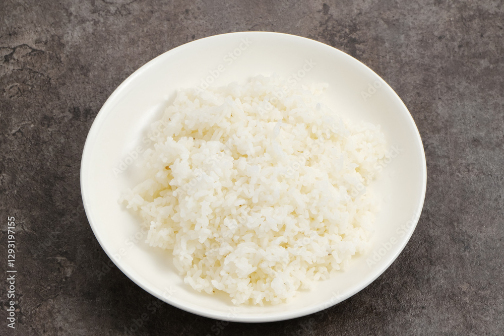 Cooked rice on white plate on dark background.
Cooked rice on white plate on dark background.