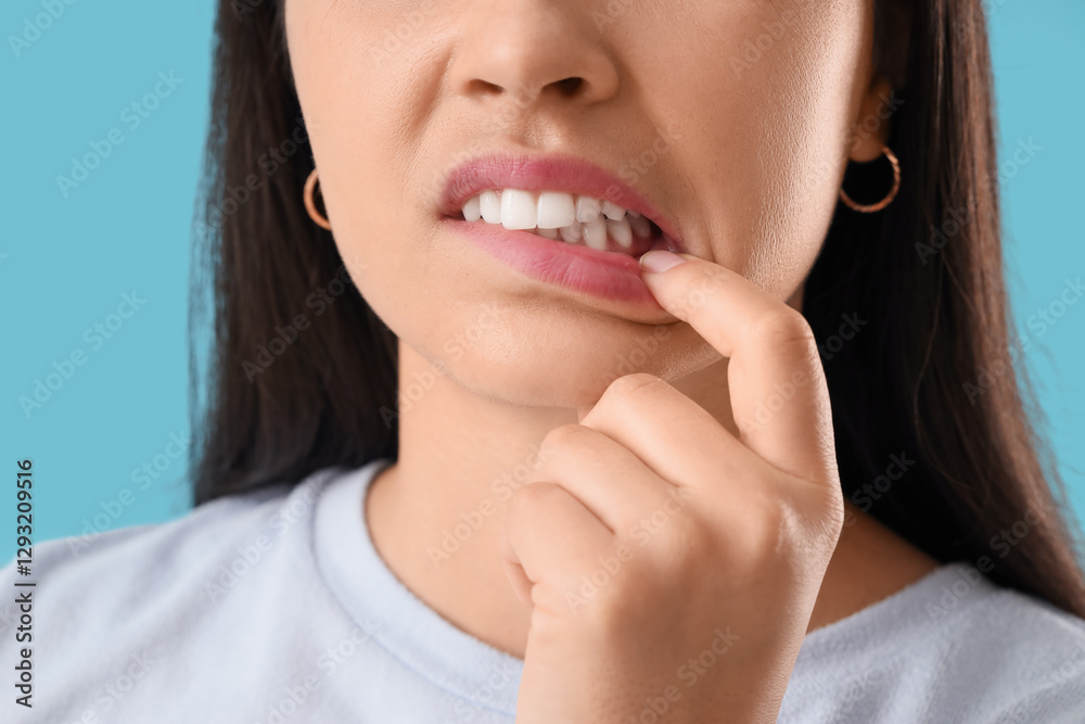 Young woman showing her teeth on blue background, closeup Young woman showing her teeth on blue background, closeup